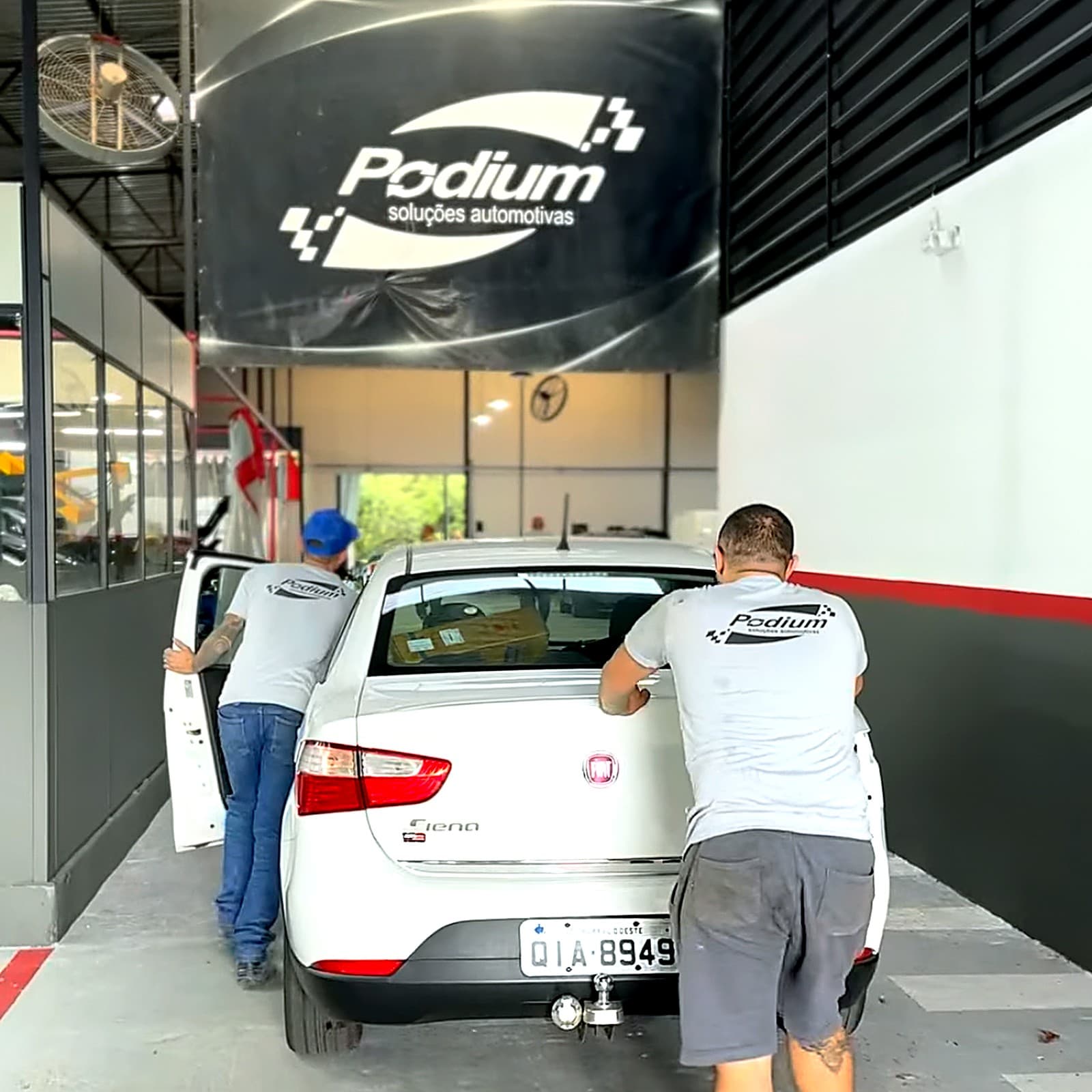Equipe Podium movendo veículo na entrada da oficina